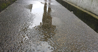 路面の水たまりにうつる人