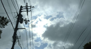 曇り空の合間から見える太陽と電柱